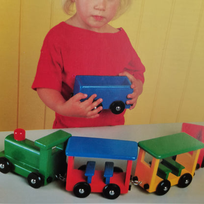 a child playing with a wooden train from the wooden toys book طفلة تلعب بقطار خشبي مصنوع من كتاب الألعاب الخشبية